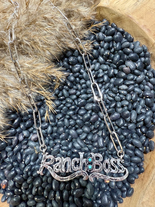 Necklace with 'Ranch Boss' pendant on a bed of black beans